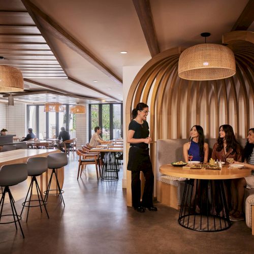 A cozy bookshelf-lined bookstore with warm lighting, arched wooden ceiling, and a person browsing among shelves.